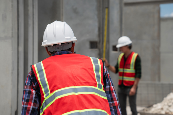 A construction worker wearing a hard hat and vest, ready to work on a construction site.